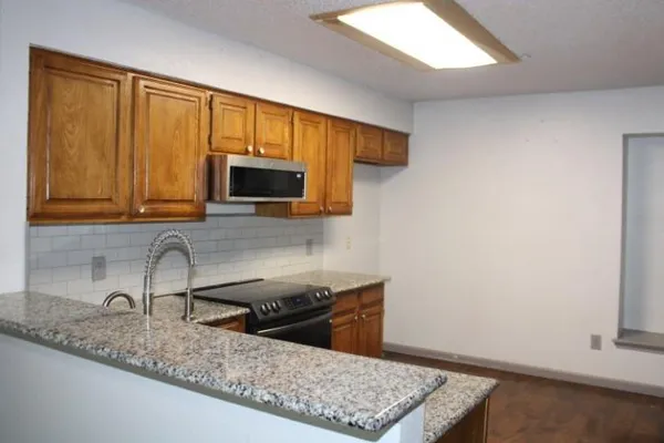 a kitchen with stainless steel appliances granite countertop a sink a microwave cabinets and a wooden floor