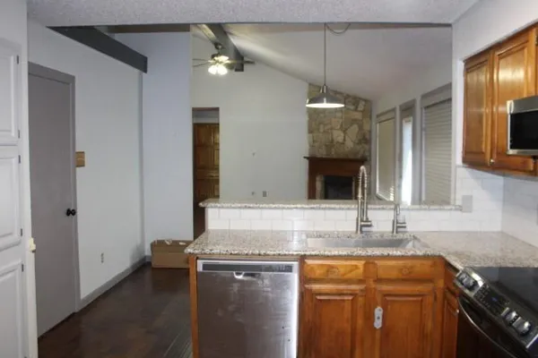 a kitchen with kitchen island granite countertop a sink cabinets and stainless steel appliances