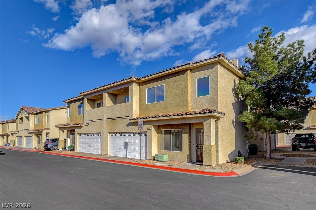 View of front of house featuring stucco siding, a tiled roof, and a garage