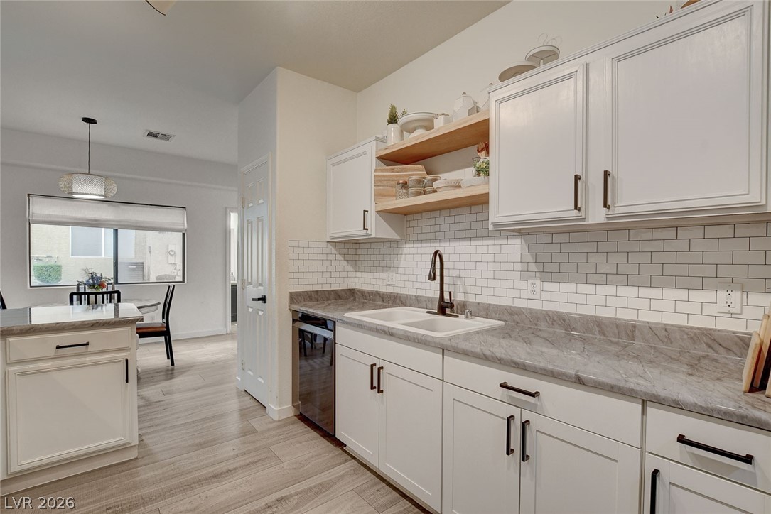 64 Brown Swallow Way Henderson, NV 89012 - Photo 18 of 42 Kitchen featuring white cabinetry, open shelves, decorative light fixtures, light wood finished floors, and dishwasher