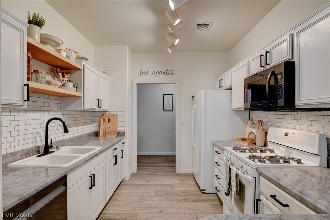 64 Brown Swallow Way Henderson, NV 89012 - Photo 2 of 42 Kitchen with white appliances, light countertops, open shelves, light wood-style flooring, and decorative backsplash