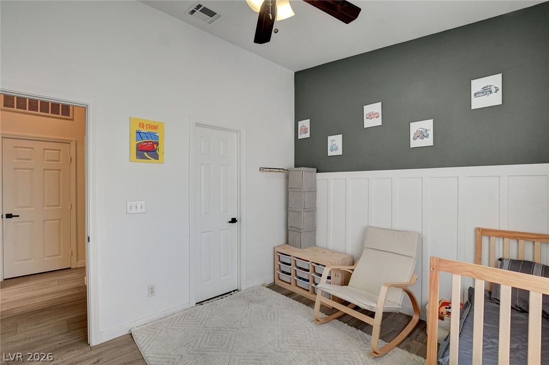 64 Brown Swallow Way Henderson, NV 89012 - Photo 30 of 42 Sitting room featuring light wood finished floors, ceiling fan, a wainscoted wall, and a decorative wall