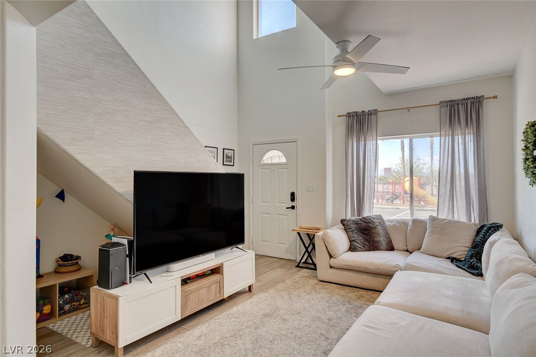 64 Brown Swallow Way Henderson, NV 89012 - Photo 9 of 42 Living room featuring healthy amount of natural light, a high ceiling, a ceiling fan, and light wood-style floors