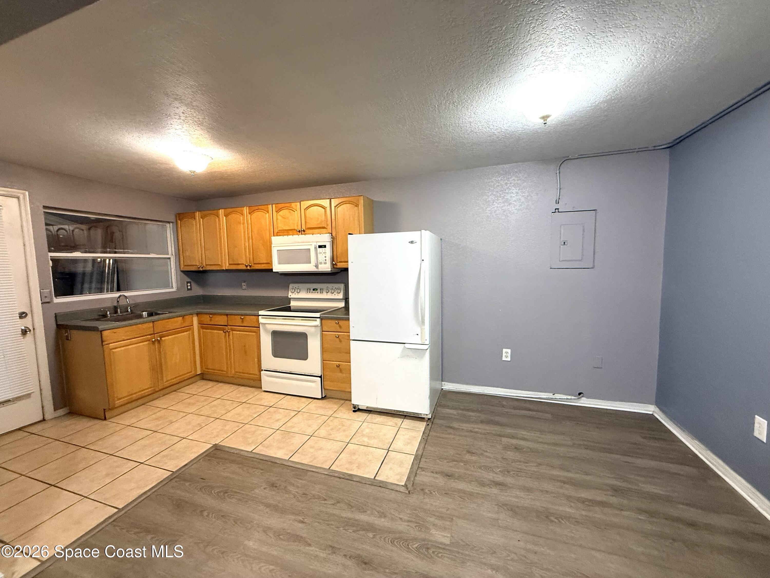 2127 Smathers Circle South, Unit B Melbourne, FL 32935 - Photo 4 of 32 a kitchen with granite countertop a refrigerator and a stove top oven