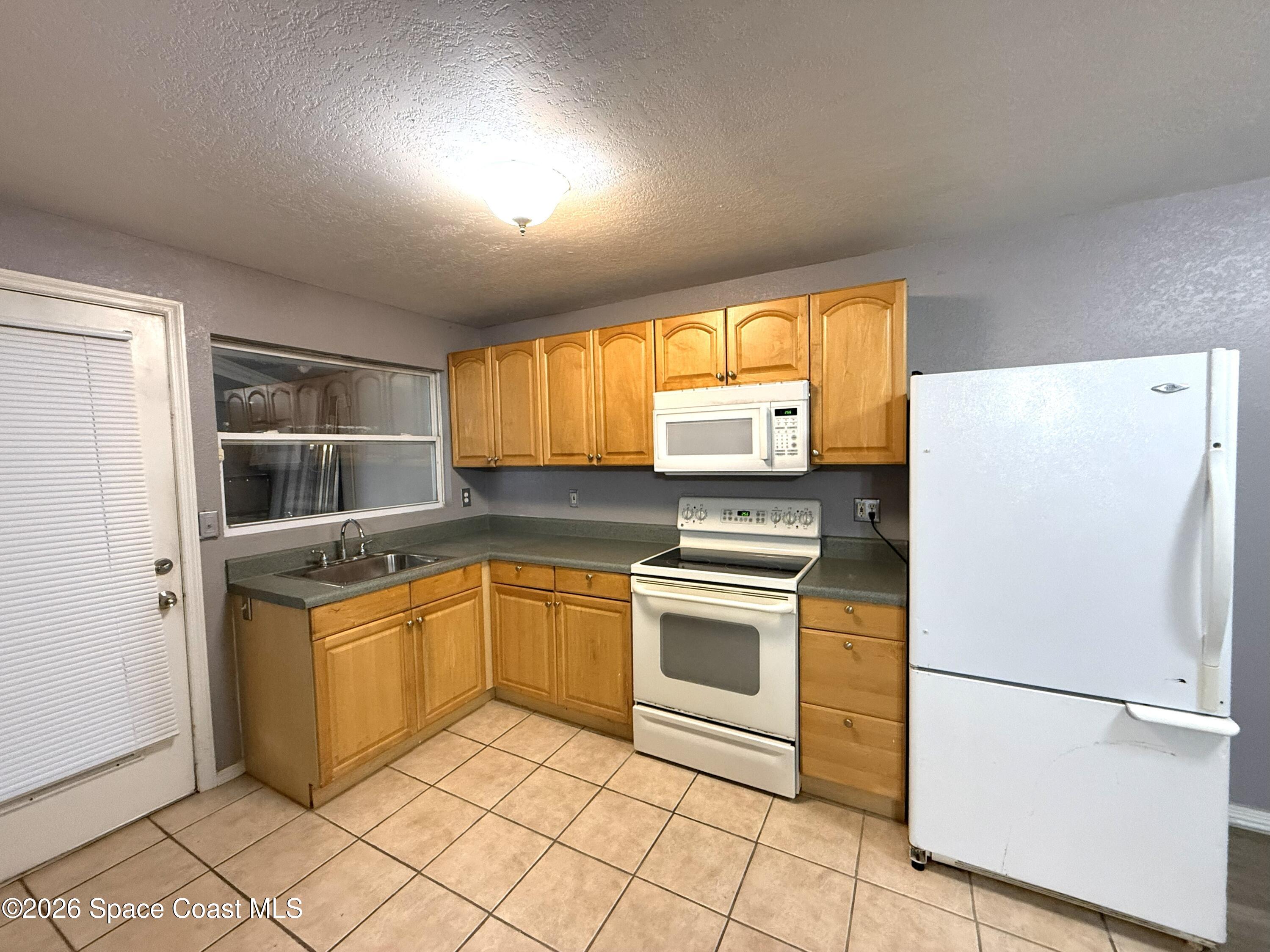 2127 Smathers Circle South, Unit B Melbourne, FL 32935 - Photo 5 of 32 a kitchen with granite countertop a refrigerator and a stove top oven