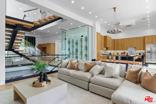 a living room with furniture kitchen view and a chandelier