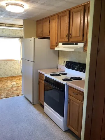 a white refrigerator freezer and a stove sitting inside of a kitchen