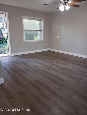 an empty room with wooden floor and windows
