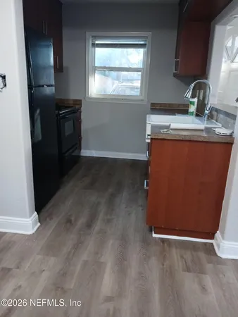 a kitchen with granite countertop a refrigerator a sink a stove and cabinets