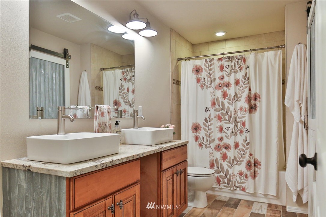 15519 OK Mill Road Snohomish, WA 98290 - Photo 20 of 32 a bathroom with a granite countertop sink a toilet a mirror a vanity and shower