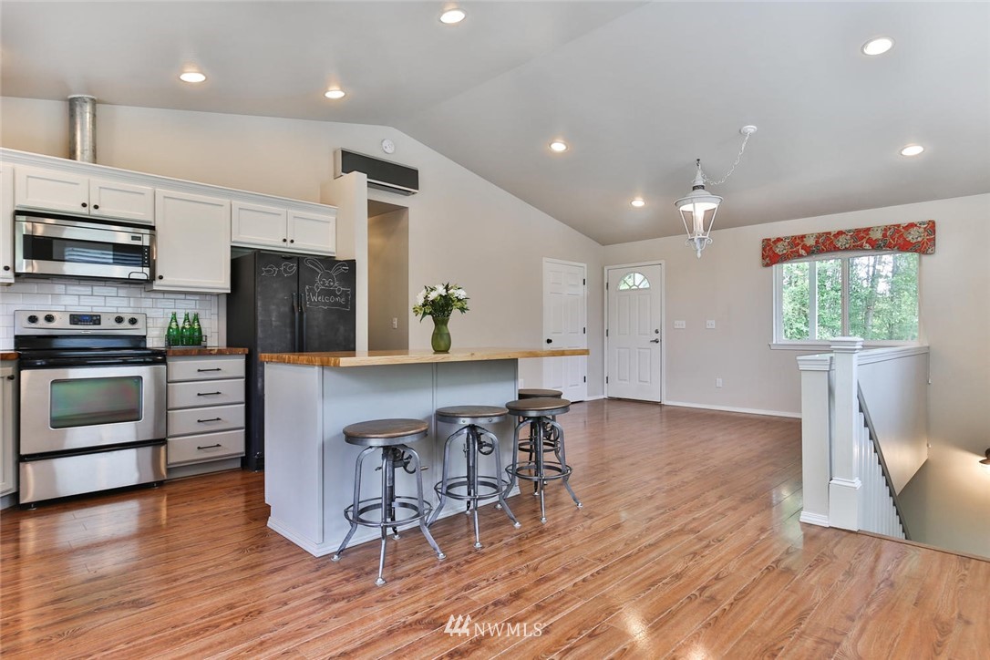 15519 OK Mill Road Snohomish, WA 98290 - Photo 4 of 32 a view of kitchen with stainless steel appliances granite countertop a stove top oven a sink dishwasher a dining table and chairs with wooden floor