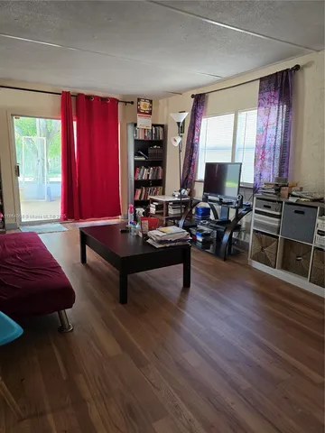 a living room with furniture a large window and wooden floor