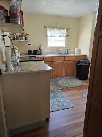 a kitchen with kitchen island a sink wooden floor and a counter top space