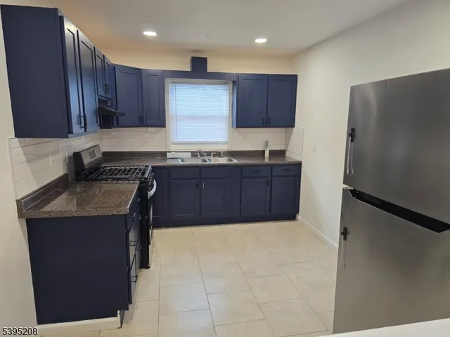 a kitchen with stainless steel appliances granite countertop a stove a refrigerator and a sink with wooden cabinets