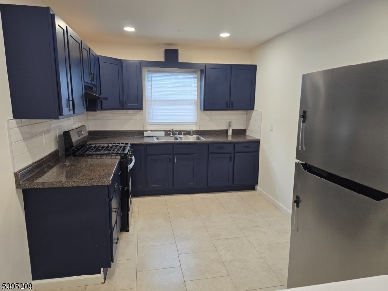67 Lindsley Avenue Irvington, NJ 07111 - Photo 2 of 12 a kitchen with stainless steel appliances granite countertop a stove a refrigerator and a sink with wooden cabinets
