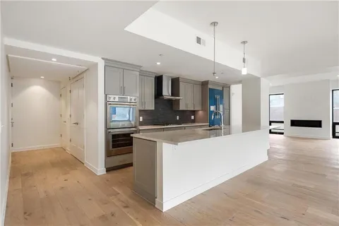 a large kitchen with stainless steel appliances a large counter top a stove and a refrigerator