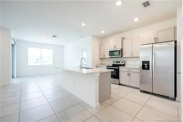 a kitchen with granite countertop a refrigerator and a stove top oven