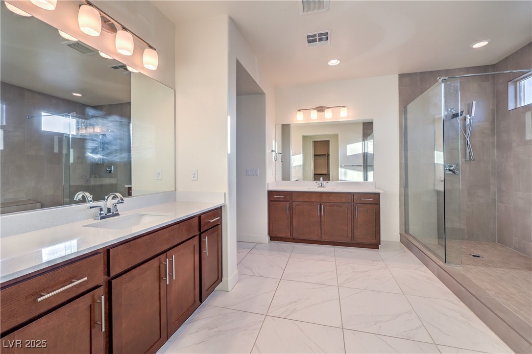 9655 Skye Star Avenue Las Vegas, NV 89166 - Photo 38 of 46 Bathroom featuring two vanities, a shower stall, light marble finish flooring, and recessed lighting