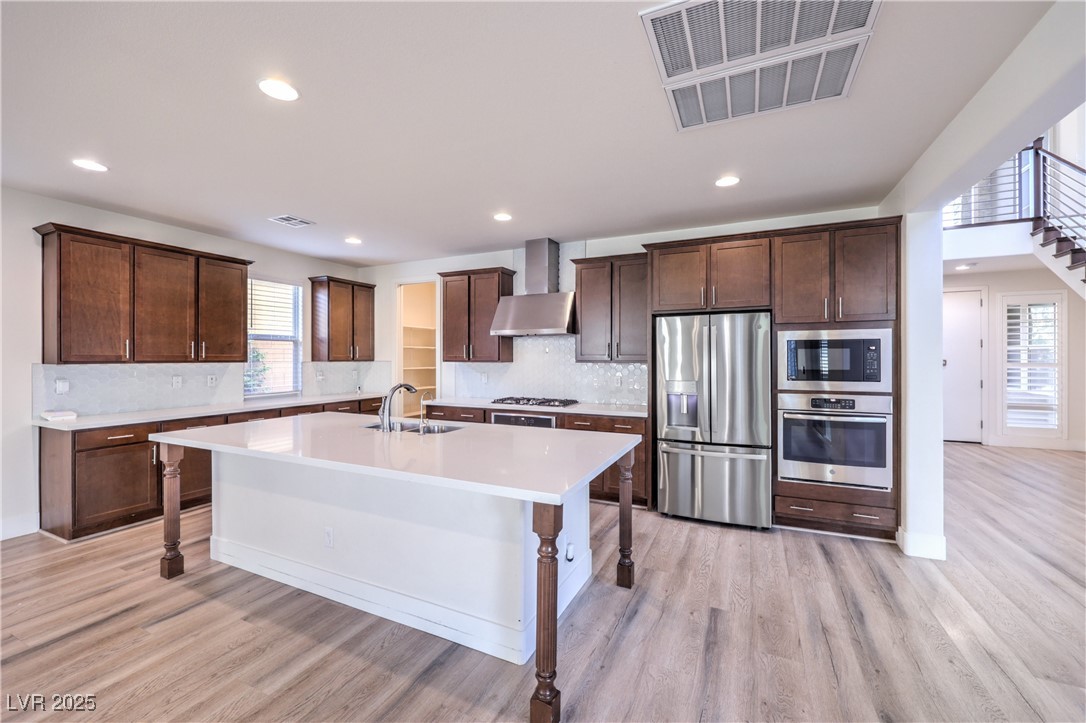9655 Skye Star Avenue Las Vegas, NV 89166 - Photo 8 of 46 Kitchen with decorative backsplash, a breakfast bar, stainless steel appliances, dark brown cabinets, and a center island with sink