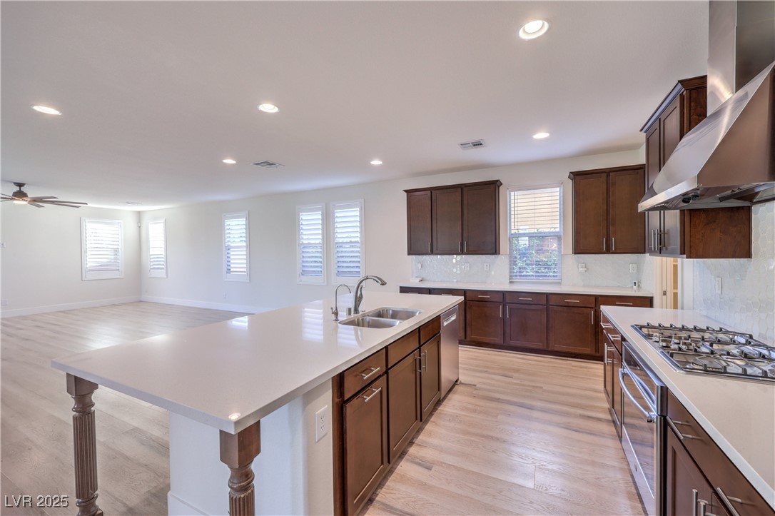 9655 Skye Star Avenue Las Vegas, NV 89166 - Photo 9 of 46 Kitchen featuring tasteful backsplash, wall chimney exhaust hood, recessed lighting, appliances with stainless steel finishes, and light wood-style flooring