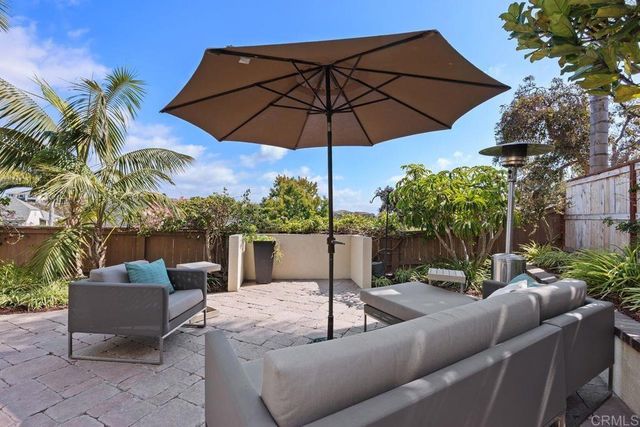 a view of a patio with couches table and chairs under an umbrella