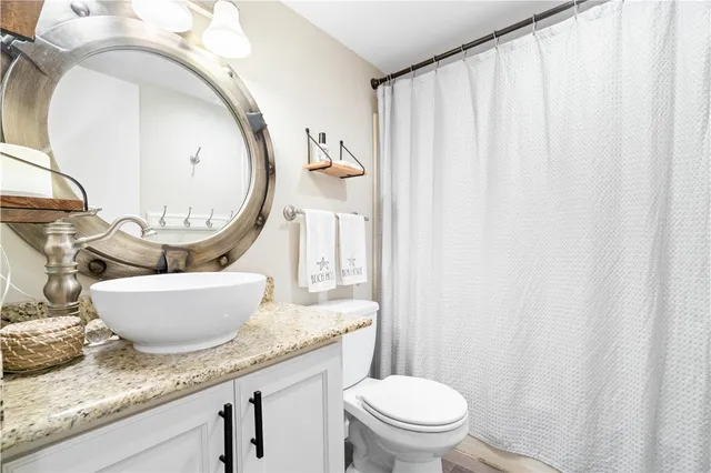 a room with a granite countertop toilet a sink and a mirror