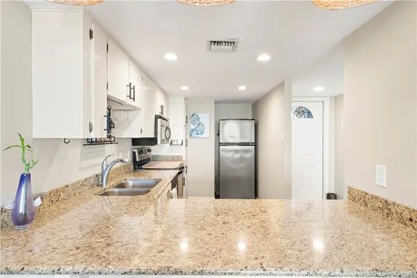 a kitchen with granite countertop a sink stainless steel appliances and cabinets