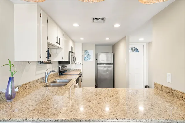 a kitchen with granite countertop a sink stainless steel appliances and cabinets