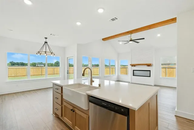 a kitchen with a stove a sink and a dining table with wooden floor