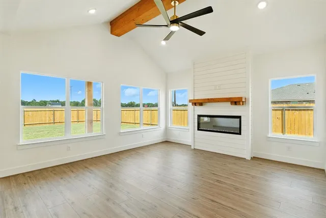 a view of an empty room with a window and wooden floor