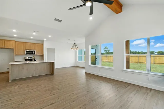 a large kitchen with stainless steel appliances a large counter top a stove and a wooden floors