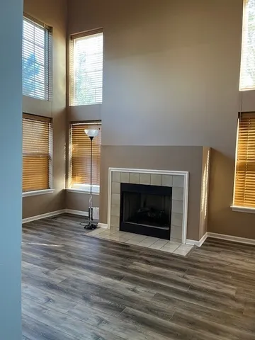 an empty room with wooden floor fireplace and windows