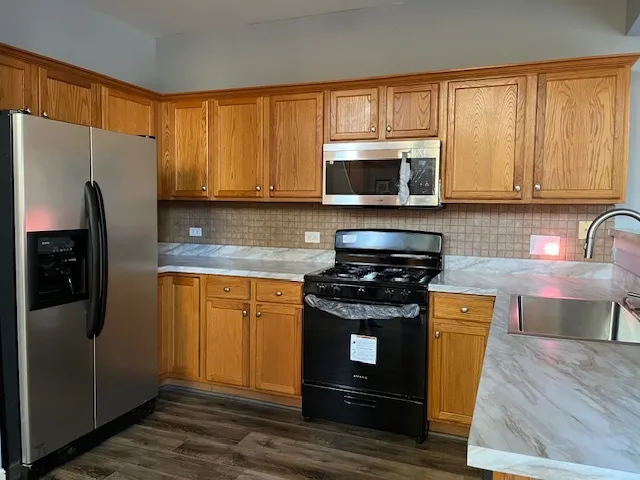 a kitchen with stainless steel appliances granite countertop a stove a refrigerator and a microwave