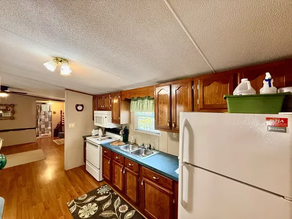 a kitchen with stainless steel appliances granite countertop a refrigerator a sink dishwasher a stove and a dining table with wooden floor