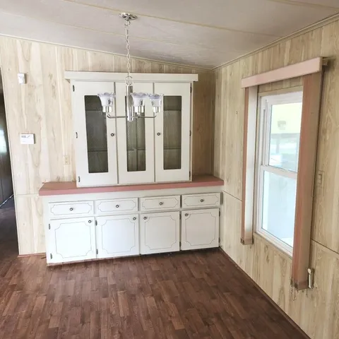 a view of a hallway with chandelier and wooden floors