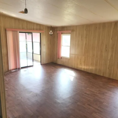an empty room with wooden floor and windows with curtains view