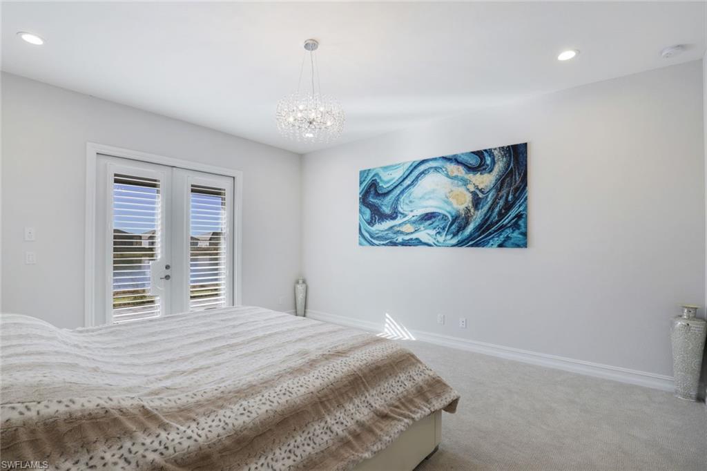 14327 Laguna Springs Lane Naples, FL 34114 - Photo 14 of 35 a bedroom with a large bed and a chandelier