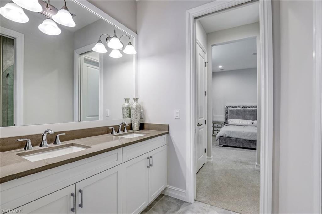 14327 Laguna Springs Lane Naples, FL 34114 - Photo 21 of 35 a en suite bathroom with a granite countertop sink a light fixture and a mirror