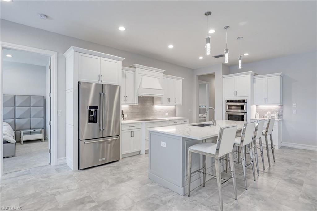 14327 Laguna Springs Lane Naples, FL 34114 - Photo 7 of 35 a kitchen with kitchen island white cabinets and stainless steel appliances