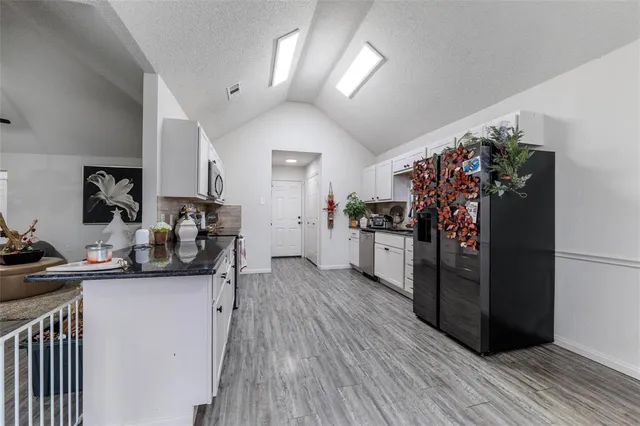 a view of a kitchen with refrigerator and wooden floor