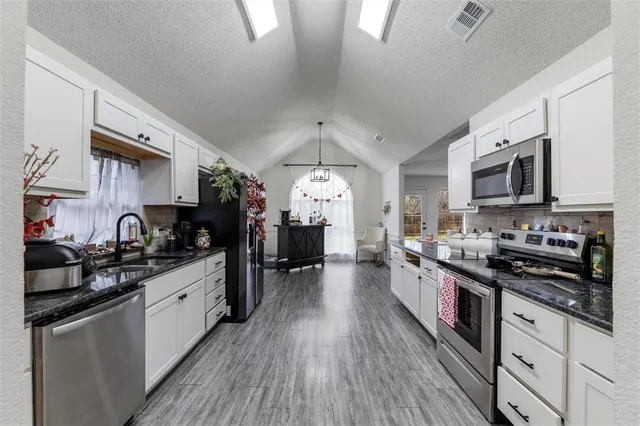 a large kitchen with stainless steel appliances granite countertop a stove a sink dishwasher and a microwave oven with cabinets