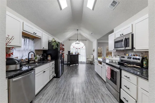 a large kitchen with stainless steel appliances granite countertop a stove a sink dishwasher and a microwave oven with cabinets