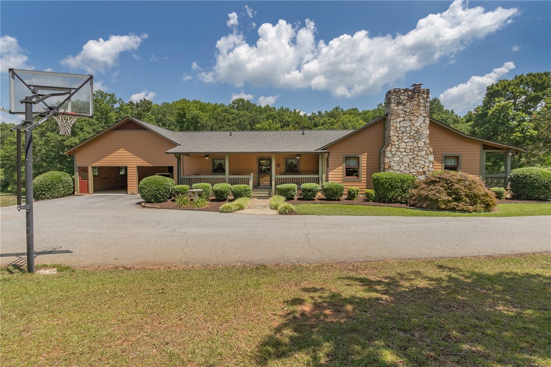 911 State Rd S-4-203 Belton, SC 29627 - Photo 6 of 49 A welcoming front porch leads to this charming home, featuring a prominent stone chimney and mature landscaping.