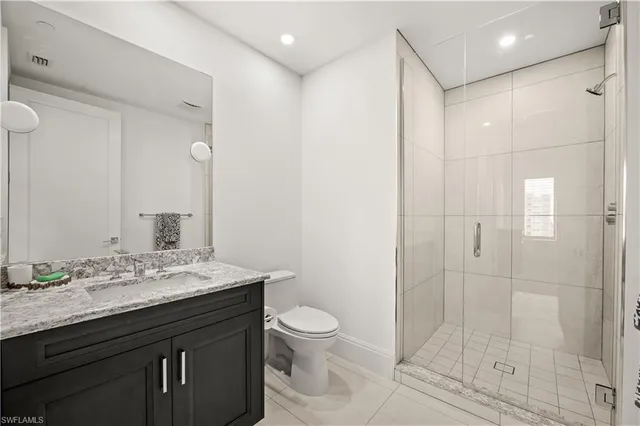 a bathroom with a granite countertop sink a toilet and shower