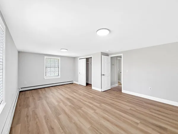 an empty room with wooden floor and windows