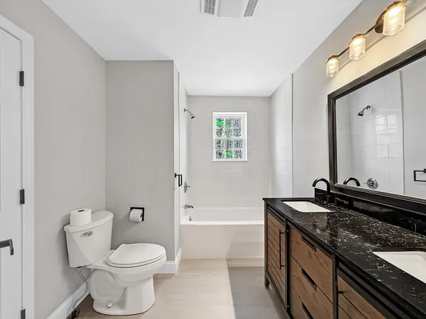 a bathroom with a granite countertop toilet a sink and a mirror