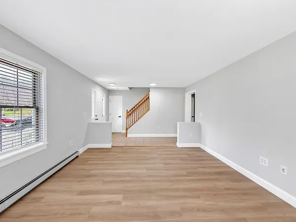 a view of an empty room with wooden floor and a window