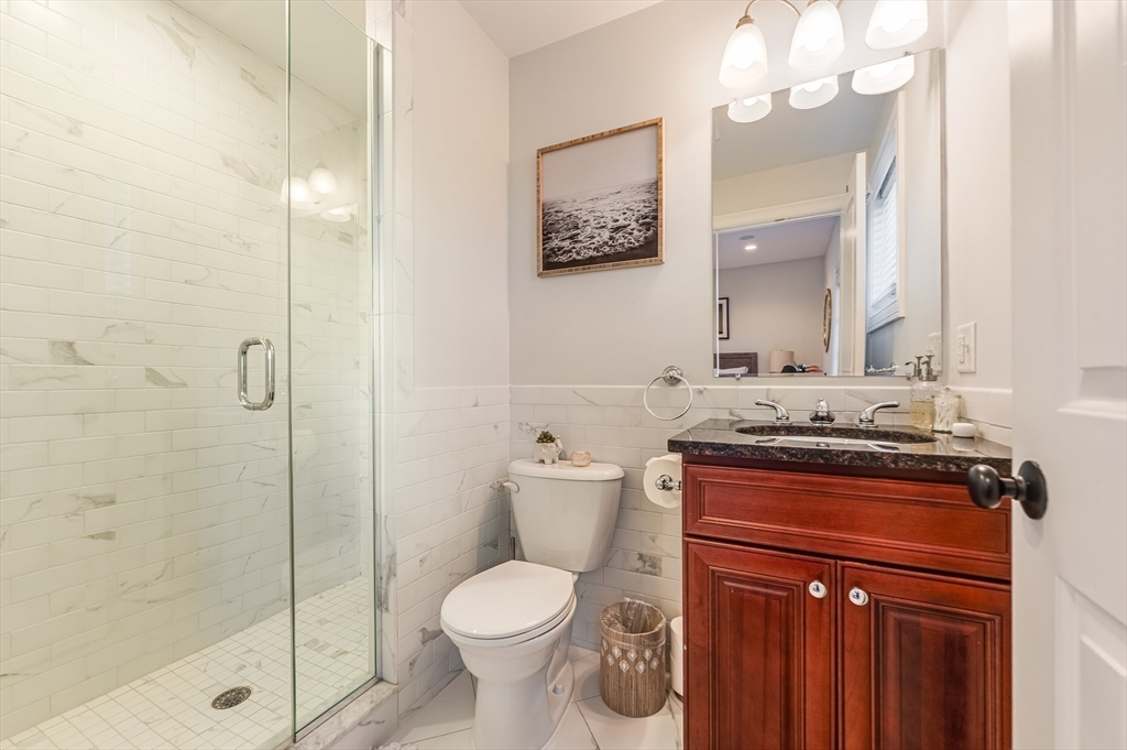 46 Rutherford Avenue Boston, MA 02129 - Photo 17 of 33 a bathroom with a granite countertop toilet a sink and a mirror