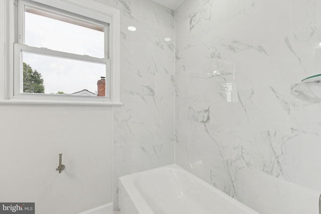 an empty room with wooden floor ceiling fan and windows