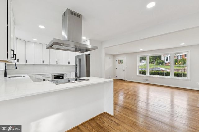 a kitchen with a stove a refrigerator and a sink with wooden floor